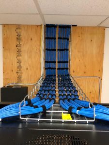 Bundles of Ethernet cables running along a metal casing up the wall and into the ceiling